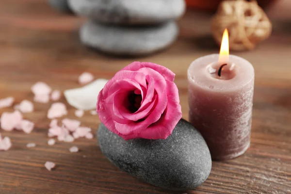 Beautiful composition of aroma candle with pebbles and flower  on wooden background — Stock Photo, Image