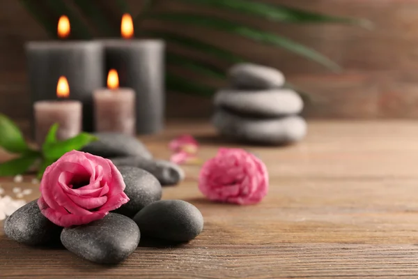 Velas grises de cera clara con rosas y guijarros sobre fondo de madera - concepto de relax — Foto de Stock