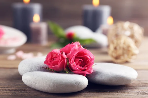 Brennende wachsgraue Kerzen mit Rosen und Kieselsteinen auf Holzgrund - Entspannungskonzept — Stockfoto