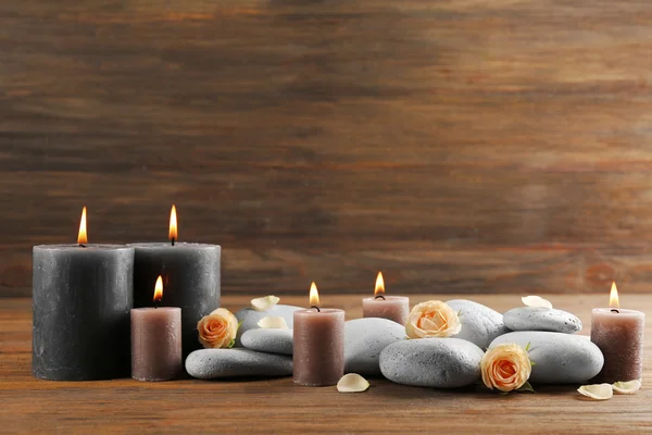 Velas grises de cera clara con rosas y guijarros sobre fondo de madera - concepto de relax — Foto de Stock