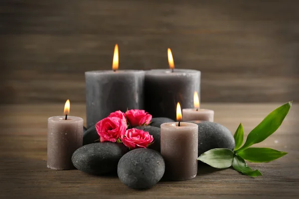 Candele grigio cera chiara con rose e ciottoli su sfondo di legno - concetto relax — Foto Stock