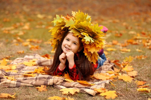 공원에 격자 무늬에 누워 노란색가 화 환에 행복 한 어린 소녀 — 스톡 사진