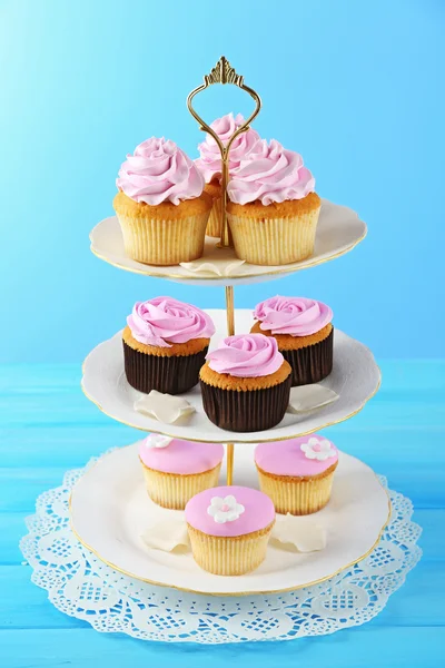 Leckere Cupcakes am Stand, auf farbigem Hintergrund — Stockfoto