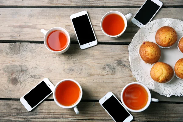 Teléfonos inteligentes, tazas con té y magdalenas —  Fotos de Stock