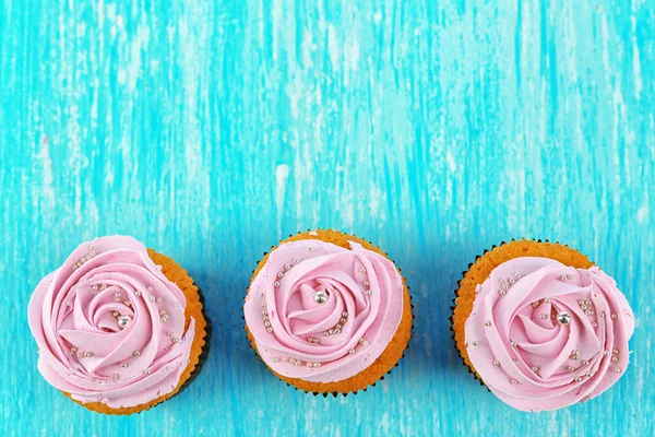 Tasty cupcakes on color wooden background — Stock Photo, Image