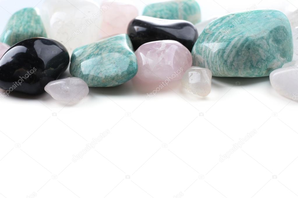Pile of stones: pink quartz, azonite, black onyx and rock crystal isolated on white background