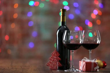 Kırmızı şarap ve Noel ışıkları arka plan üzerinde ahşap masa Noel süsler