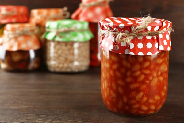 Frascos con verduras y frijoles en vinagre sobre fondo de madera —  Fotos de Stock