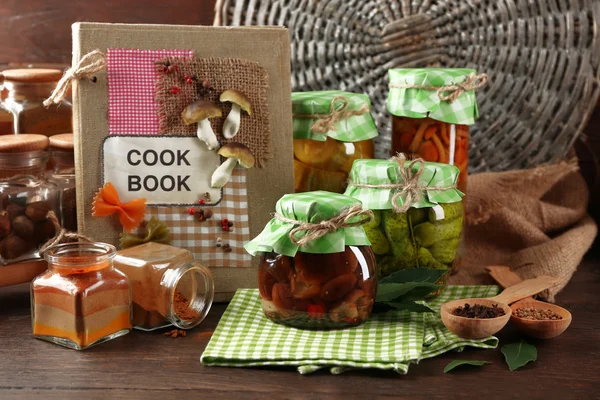 Potten met ingemaakte groenten, bonen, specerijen en keukengerei op houten achtergrond — Stockfoto