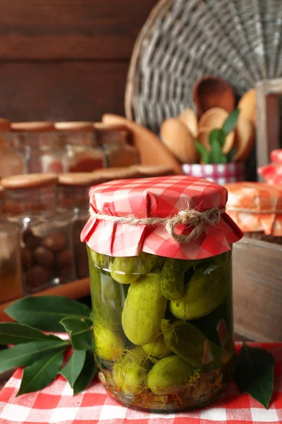Jars with pickled cucumbers, spices and kitchenware on wooden background — Stock Photo, Image