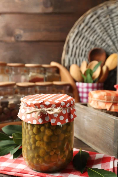 Vasi con verdure sottaceto, fagioli, spezie e utensili da cucina su sfondo di legno — Foto Stock