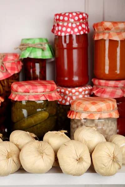 Potten met ingemaakte groenten en bonen op houten plank — Stockfoto