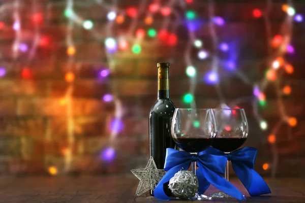 Vinho tinto e enfeites de Natal na mesa de madeira na parede de fundo de tijolo com luzes de Natal — Fotografia de Stock