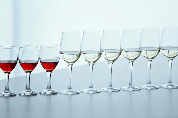 Pohárky s bílou, červená a růžová vína na dřevěný stůl na světlé pozadí — Stock fotografie