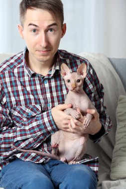 Yakışıklı delikanlı bir kedi evde kanepede holding
