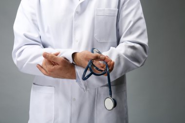 Çapraz elleri ve gri arka plan üzerinde stetoskop ile Doktor, yakın çekim