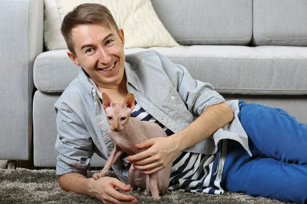 Giovane bell'uomo si trova con il gatto sul pavimento a casa — Foto Stock