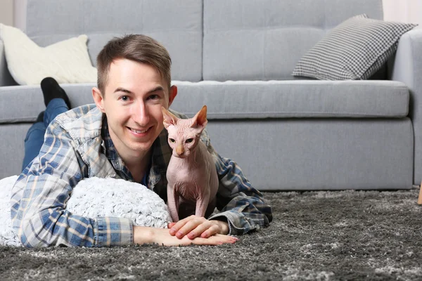 Young handsome man lies with cat on floor at home — Stock Photo, Image