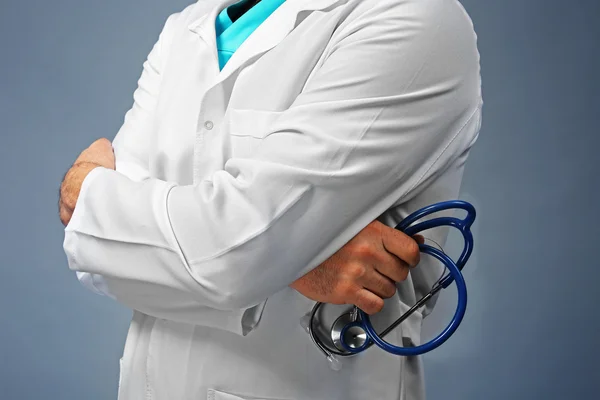 Лікар з схрещеними руками і стетоскопом на сірому фоні, крупним планом — стокове фото