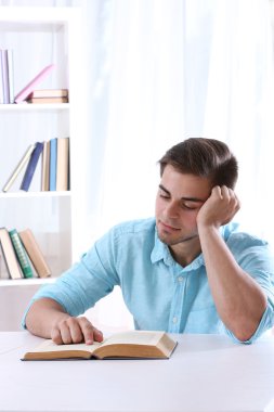 Genç adam masada kitap okumak