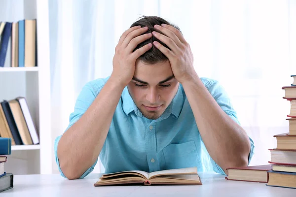 Jovem homem lendo livro à mesa — Fotografia de Stock