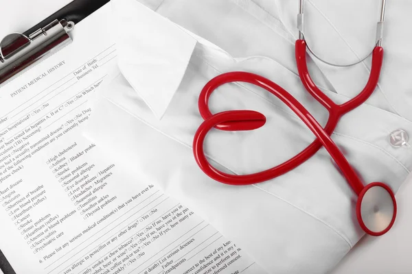 Stetoscopio rosso, cartella clinica e uniforme — Foto Stock