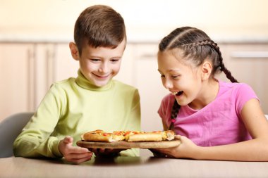 Çocuklar pizza yiyor.  
