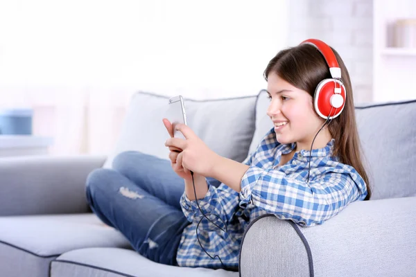 Menina bonita ouvindo música no sofá — Fotografia de Stock