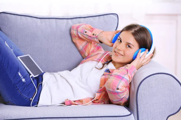 Hezká dívka poslechu hudby na pohovce — Stock fotografie