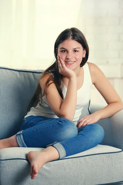 Jovem menina bonita sentado no sofá — Fotografia de Stock