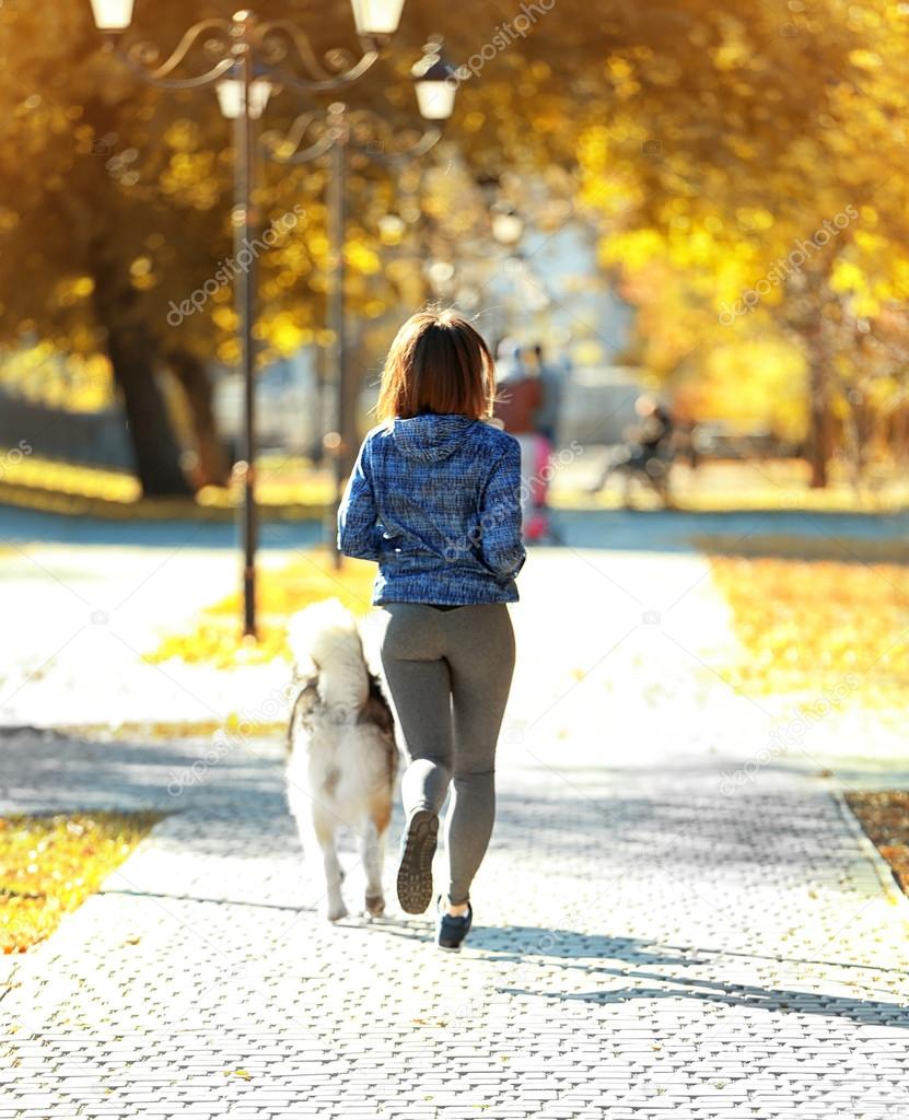 woman jogging with her dog in park