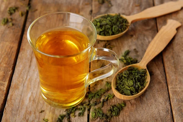 Coupe en verre de thé et cuillères avec des feuilles — Photo