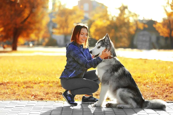 Kvinna promenader med hund i parken — Stockfoto