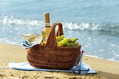 Piknik sepeti şişe şarapla kum plaj