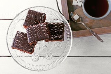 Tablo ile çikolatalı kek ve bir bardak çay beyaz ahşap arka plan üzerinde servis