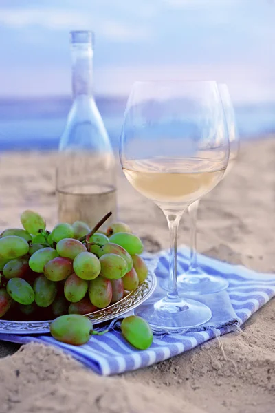 Composição romântica de vinho branco e uva na praia de areia — Fotografia de Stock
