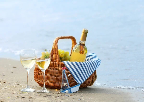 与瓶酒在沙滩上野餐篮子 — 图库照片