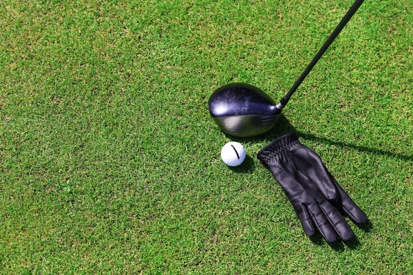 Golf clubs met bal en zwarte handschoen op een groene gras, close-up — Stockfoto