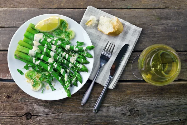Served wooden table with asparagus dish and wine, close up — Stock Photo, Image