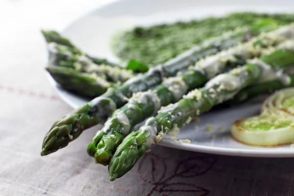 Prato de espargos delicioso com cebolas e molho verde na mesa, close-up — Fotografia de Stock