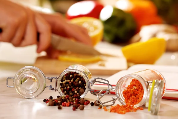 Meng de peper en gedroogde wortelen kruiden in de glazen pot op keukentafel — Stockfoto