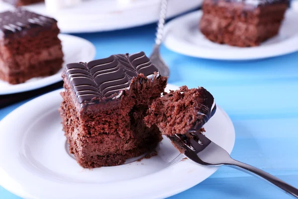 Mesa servida con pastel de chocolate sobre fondo azul — Foto de Stock