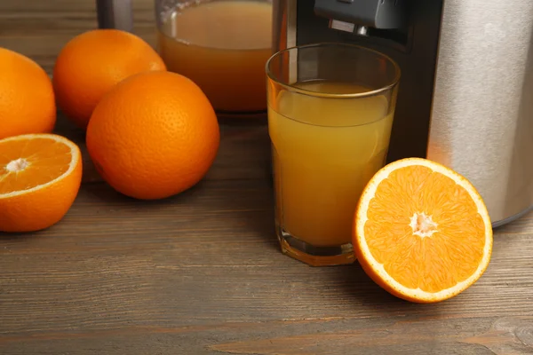 Paslanmaz suyu extractor cam ahşap zemin üzerine portakal suyu ile yakın çekim — Stok fotoğraf