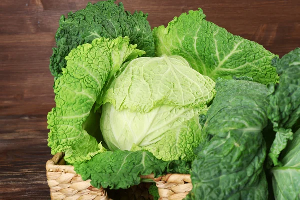 Savoy cabbage in wicker basket on wooden background, close up — Stock Photo, Image