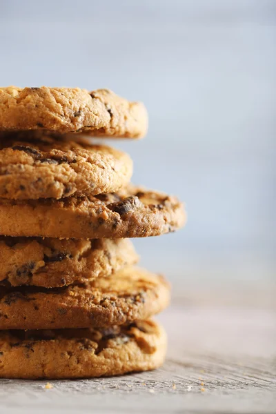 Zblízka pohled zaměření na cookies s čokoládové drobky na dřevěný stůl rozmazané modré pozadí — Stock fotografie