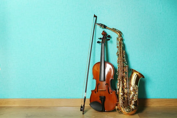 Biola dan saksofon di lantai dengan latar belakang biru — Stok Foto