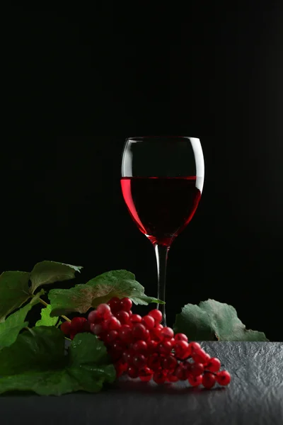 Un verre de vin et de raisins rouges, sur fond gris-noir — Photo