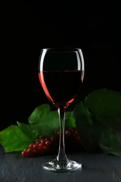 Ένα ποτήρι του κρασιού και κόκκινα σταφύλια, σε φόντο γκρι-μαύρο — Φωτογραφία Αρχείου