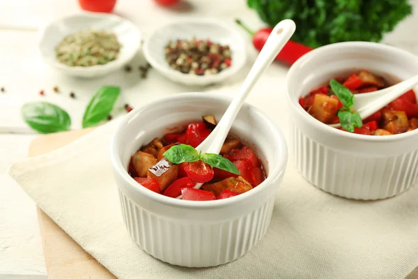 Chutné vegetariánské ratatouille z lilku, squash, rajčata v miskách na dřevěný stůl pozadí — Stock fotografie