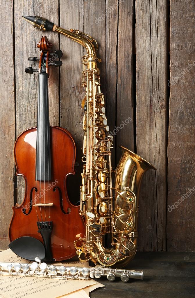 Musical instruments saxophone, violin and flute with notes on wooden